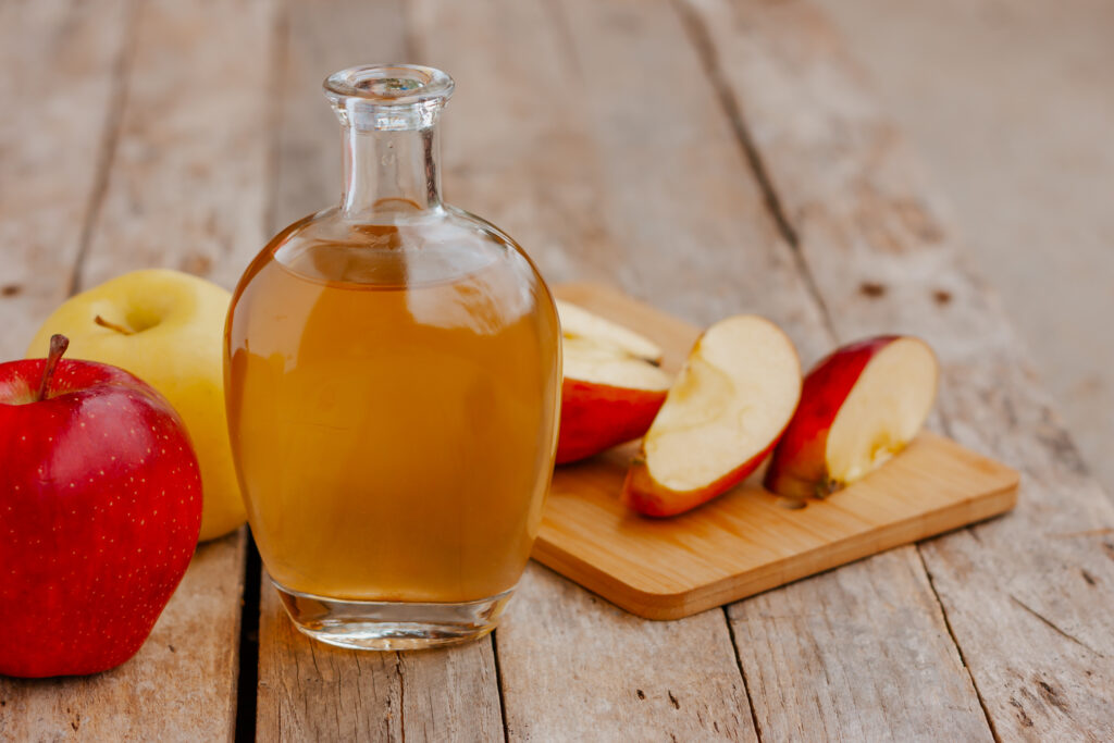 Apples and apple cider vinegar on a wooden deck